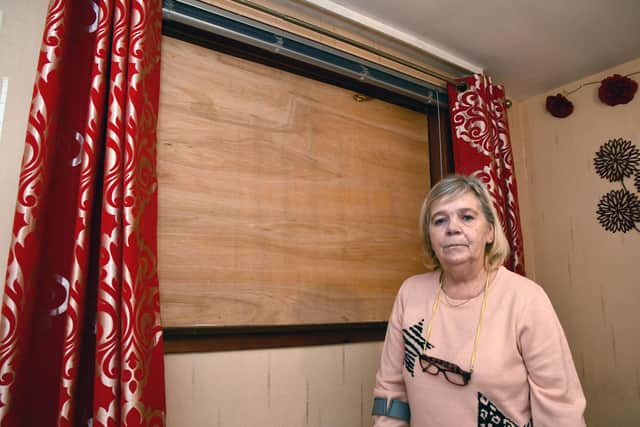 Margaret Robertson beside the boarded up bedroom window that has not been replaced since falling out in July. Picture: Michael Gillen