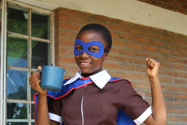 Upile with the daily mug of vitamin-enriched porridge that she receives from Mary’s Meals.