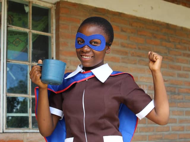 Upile with the daily mug of vitamin-enriched porridge that she receives from Mary’s Meals.