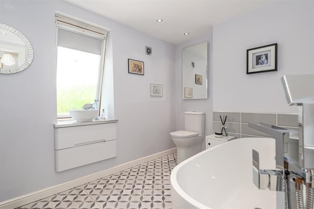 The luxury bathroom is fully tiled with a free standing double ended bath with waterfall tap, sleek enclosed curved shower cubicle, underfloor heating, and built-in ceiling speakers.