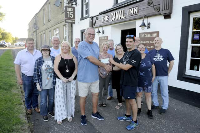 Robert Heeps, of The Canal Inn,  watched on by regulars as he presents a cheque for £500 to Kris Elliot of Team Noble in 2018. Fundraisers rowed across the Atlantic for The Fire Fighters Charity in memory of watch manager John Noble, who died in a road traffic collision in January 2008. Picture: Michael Gillen.