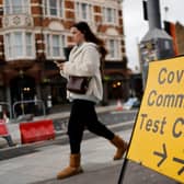 A pedestrian walks past a directional sign for a Covid-19 test centre. Photo by TOLGA AKMEN/AFP via Getty Images