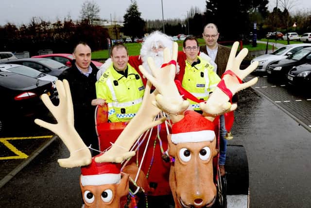 Larbert Round Table members, Richard Whitefield, left) and Grant Keenan, along with Santa hand over the cash to Sergeant David Ferguson and Sergeant Ally Goldie. Picture: Michael Gillen