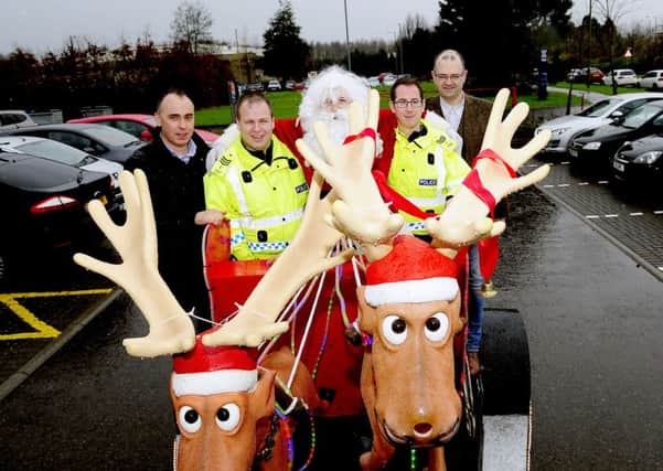 Larbert Round Table members, Richard Whitefield, left) and Grant Keenan, along with Santa hand over the cash to Sergeant David Ferguson and Sergeant Ally Goldie. Picture: Michael Gillen