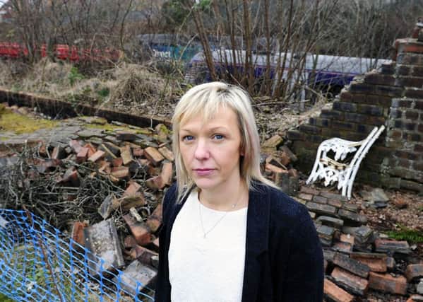 Julie Connelly stands next to the collapsed wall