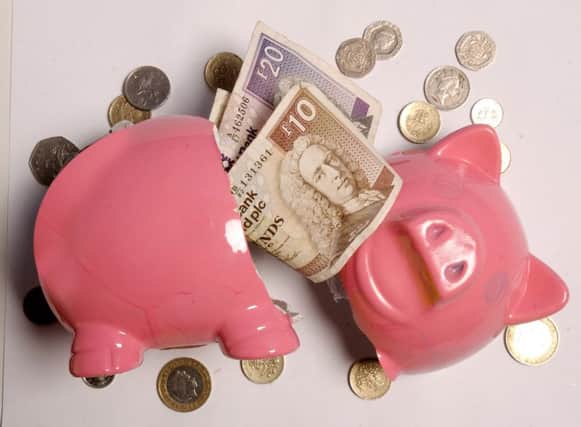 A broken pink piggy bank with notes and coins spilling out of it.