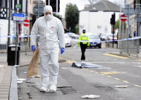 A police forensic officer searches the scene in Lower Newmarket Street for evidence. Picture: Michael Gillen