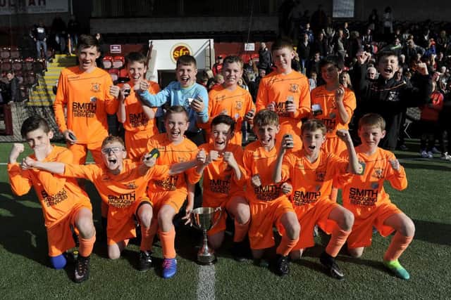The under-13s captain lewis McFarlane lifted the cup after the win over Cumbernauld. Pic by Michael Gillen.