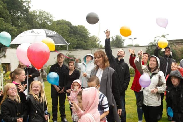 Parents and siblings release balloons in the childrens' memory