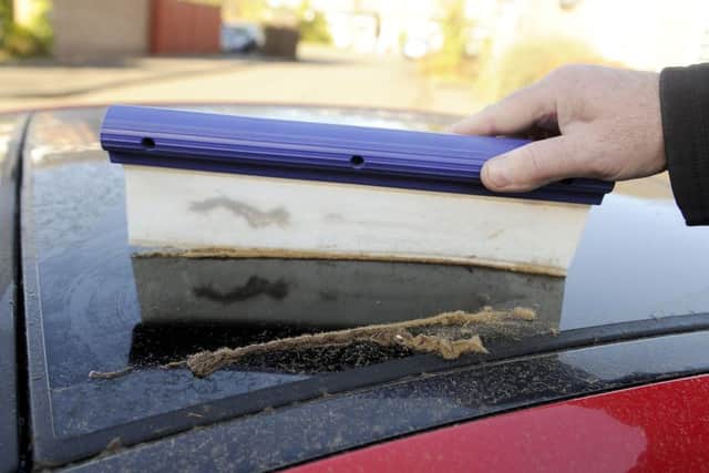 A resident scrapes the sawdust from his car