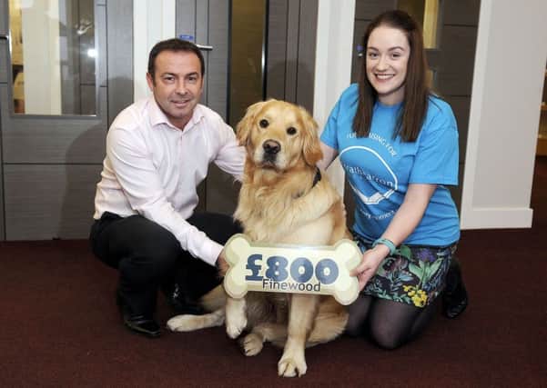 Willie Anderson, managing director of Finewood Doors, with the held of Jax, the two year old Golden Retriever presents Â£800 to Claire MacDonald, business development fundraiser for Strathcarron Hospice.  Picture: Michael Gillen.