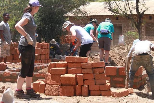 Anne, left, joins volunteers working to turn a pile of bricks into a family home.