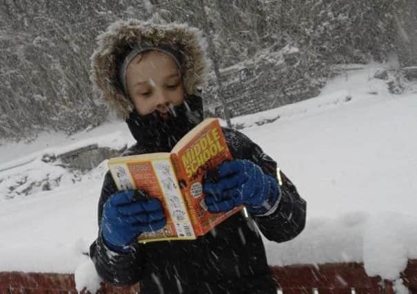 Bankier Primary pupil reads in the snow.