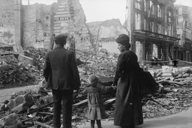 A refugee family returning to Amiens, looking at the ruins of a house, September 17, 1918. © IWM (Q 11341)