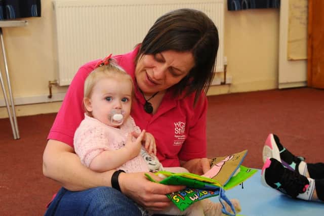 14-month-old Jamie-Leigh enjoys a book with Pamela McMillan, Home Start group worker.