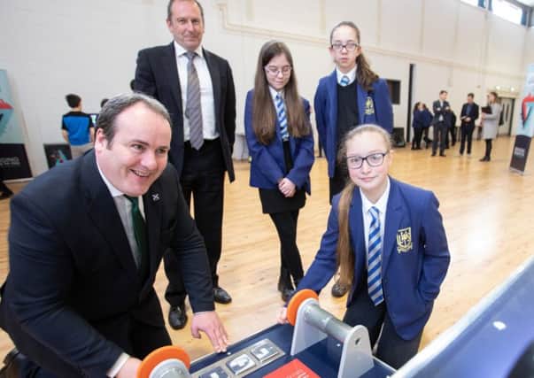 Minister Paul Wheelhouse and Larbert High School pupil Kiera Sprang (12) study an energy gizmo at the exhibition, watched by Glasgow Science Centre chief executive Stephen Breslin and students.