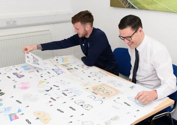 Falkirk FC's Jordan McGhee and Specsavers'  Zander McNaughton look at the entries for thjs year's family fun day competition.