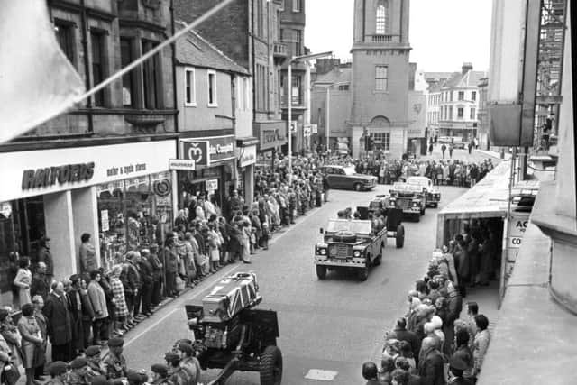 Pedestrians stop in silent tribute as the coffins of two part-time paratroopers killed in the River Trent disaster are carried through Falkirk High Street in October 1975. 10 members of the 131 Independent Squadron TA regiment were killed at Cromwell Weir in Nottinghamshire.