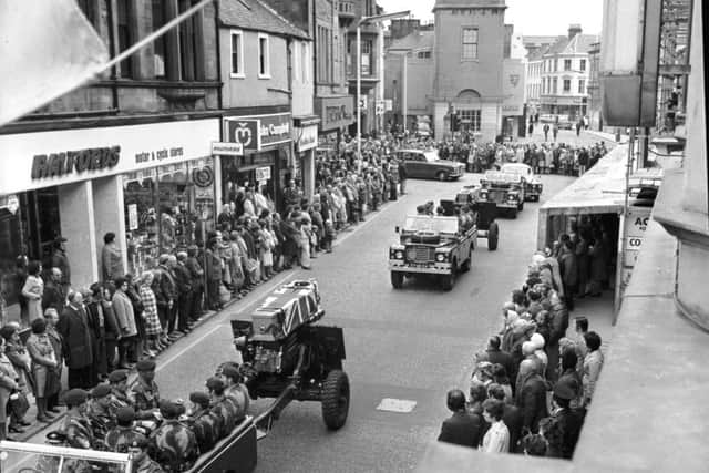 Pedestrians stop in silent tribute as the coffins of two part-time paratroopers killed in the River Trent disaster are carried through Falkirk High Street.