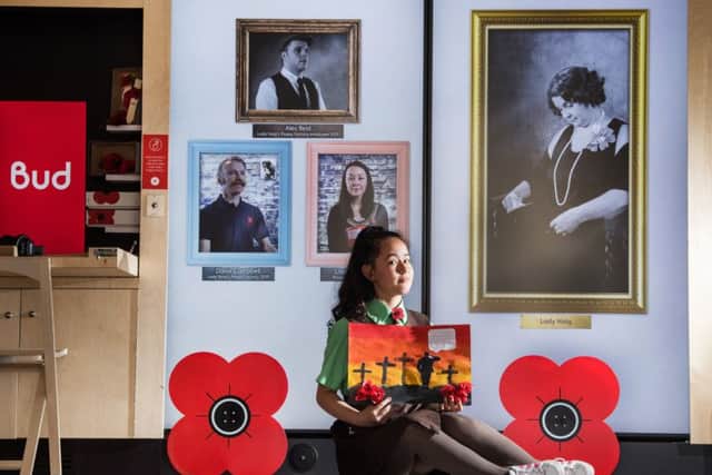 Painting a picture...St Denis's PS P6 pupil Sara Samadi under the four portraits which come to life to tell the story of the poppy. (Pic: John Devlin)