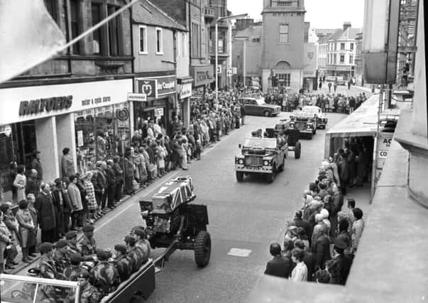 Pedestrians stop in silent tribute as the coffins of two part-time paratroopers killed in the River Trent disaster are carried through Falkirk High Street in October 1975.