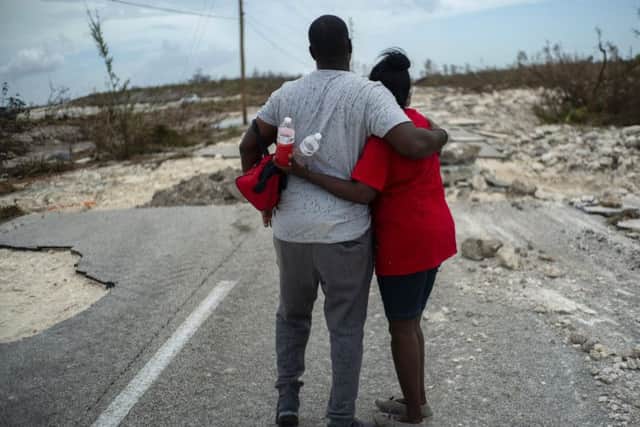 A couple survey a road in Grand Bahama which looks like it has been caught up in the middle of a war - but nature is the culprit.