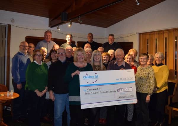 Springfield Golf Society Gents captain Brian Smith and Ladies Captain Cathie Donnelly handing over a cheque for £7,500 to Children 1st's community fundraiser Regan Johnson in front of society members.